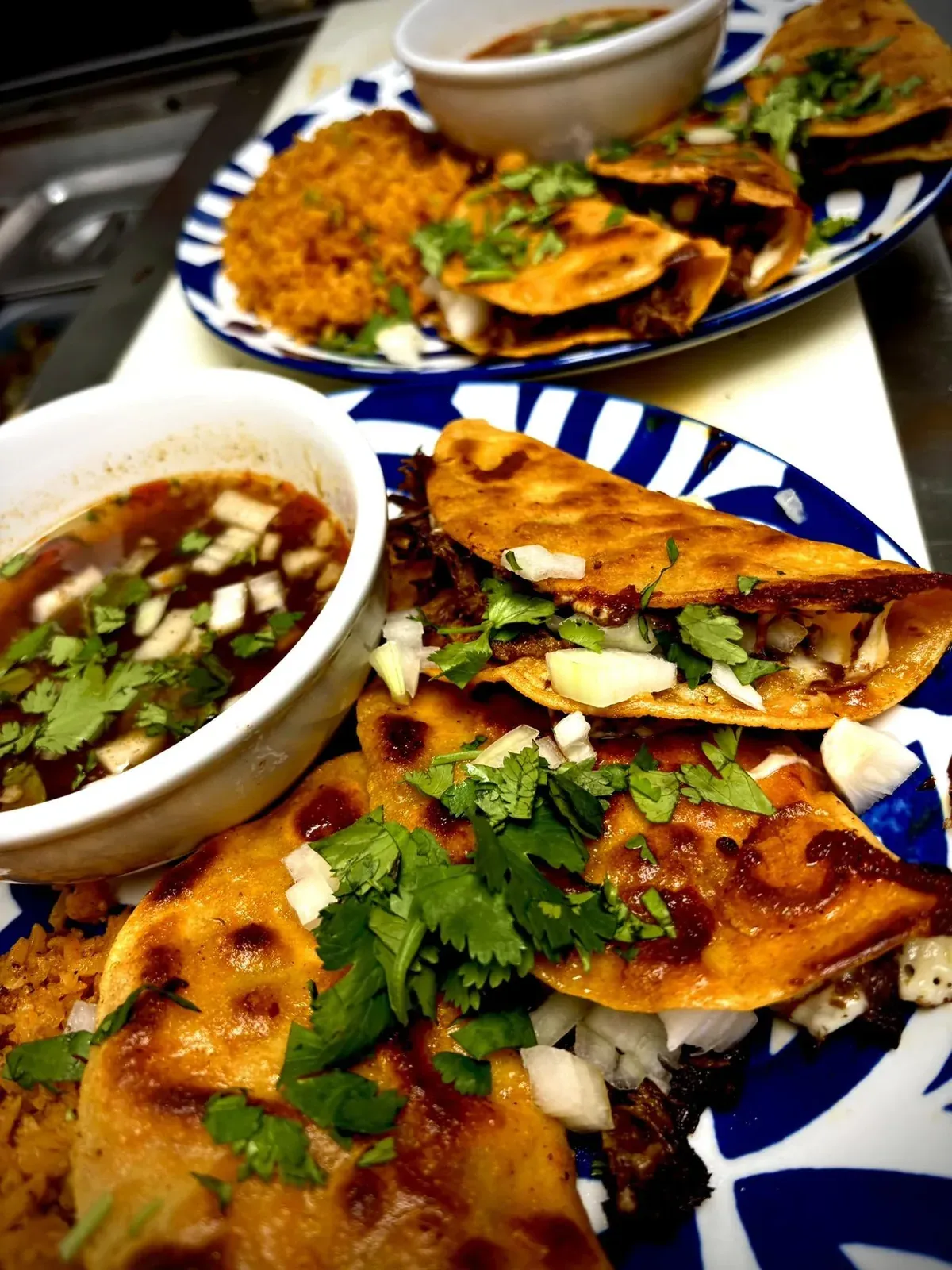 Quesadillas dorées et bol de consommé, sur assiette de talavera.