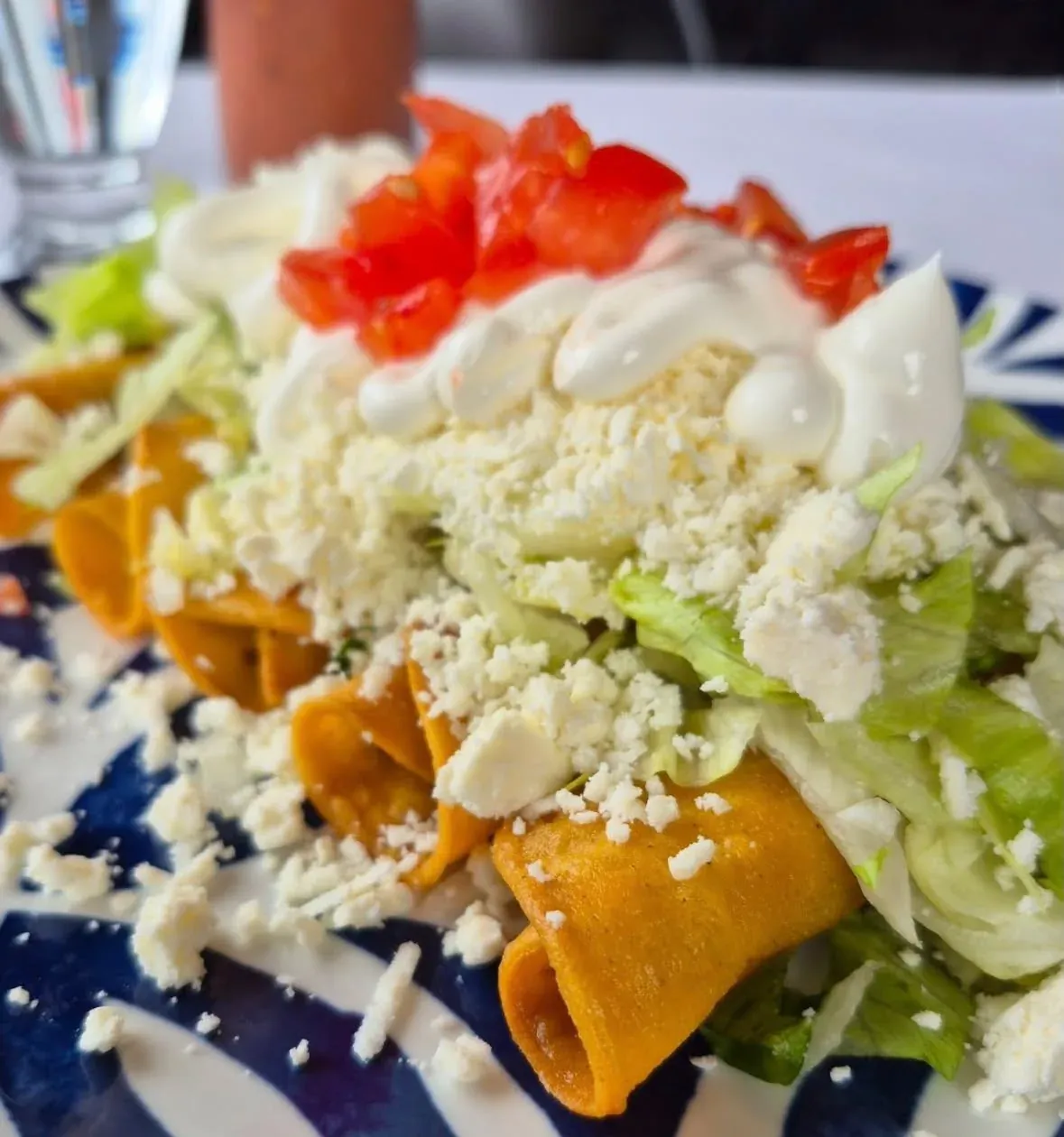 Taquitos roulés, crème, fromage râpé et laitue.